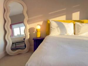 a bedroom with a white bed with a large mirror at Zozy Clitterhouse in London +9 photos
