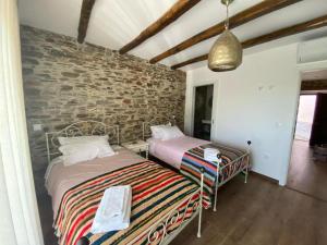 two beds in a room with a brick wall at Casa da Meia Encosta in Arganil