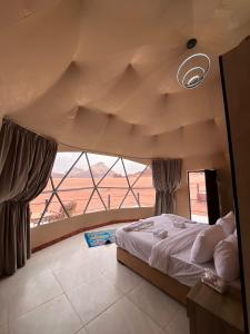 a bedroom with a large bed and a large window at Wadi rum camp teem in Wadi Rum
