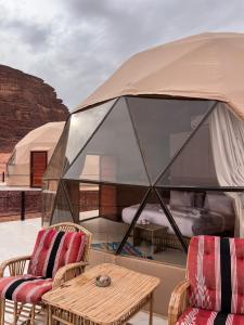 a tent with two chairs and a table on a patio at Wadi rum camp teem in Wadi Rum