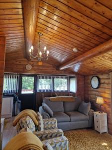 a living room with a couch and a chandelier at Cabin Retreat in Trawsfynydd +13 photos