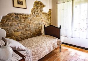 a bed in a room with a stone wall at B&B Cortebonomini apartment in Neviano degli Arduini +31 photos