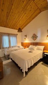 a bedroom with two beds and a wooden ceiling at Pousada Caponga Praia Mar in Cascavel +11 photos