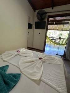 a bed with two white sheets on top of it at Pousada Meraki Paraty Mirim in Paraty