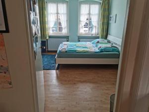 a small bedroom with a bed and two windows at Grenzstübchen in Hötensleben