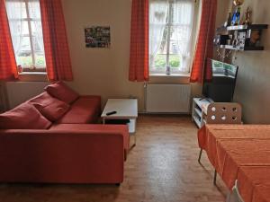 a living room with a red couch and two windows at Grenzstübchen in Hötensleben