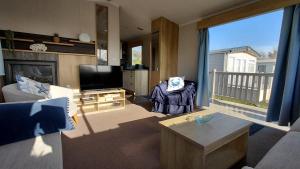 a living room with a couch and a television at Driftwood at Freshwater Beach Holiday Park in Burton Bradstock