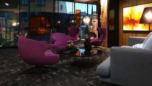 a living room with purple chairs and a table at Hotel Arka in Skopje