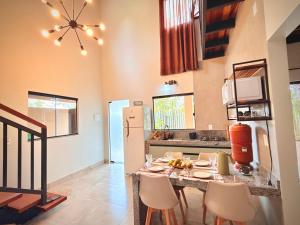 a kitchen with a table with chairs and a refrigerator at Claruá Chalés- Loft Caju- Pé direito duplo, 3min de carro do Rio- Conforto e Natureza dentro da cidade in Cavalcante +30 photos
