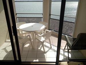 a table and chairs on a balcony with a view of the water at les pieds dans l'eau 1-Piscine chauffée in Le Barcarès