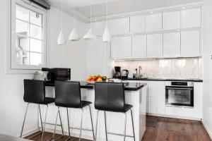 a white kitchen with black chairs and a counter at Sunset Stay in Malmö
