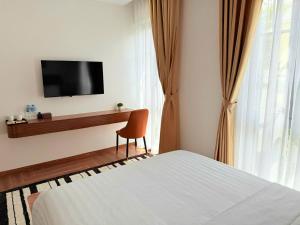 a bedroom with a bed and a desk with a television at KHEM BEACH Hotel in Phú Quốc