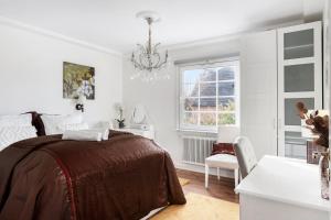 a white bedroom with a bed and a chandelier at Sunset Stay in Malmö