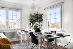 a dining room with a table and chairs and windows at Sunset Stay in Malmö
