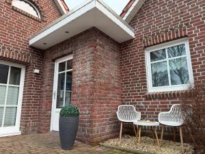 a brick house with two chairs and two windows at Ferienwohnung Kurze Auszeit 24 Std Check in in Hesel