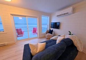 a living room with a blue couch and a balcony at Saltwater Steeple in Port Saunders