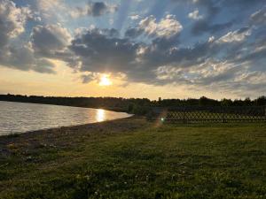 a sunset over a body of water with the sun setting at Seeperle am Concordia See in Friedrichsaue