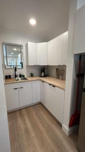 a kitchen with white cabinets and a wooden floor at #4 Hygge Hus Hotel - Double Room Suite Connectable in Andrews