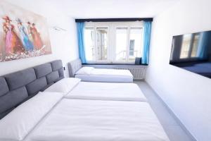 a room with two white beds and a window at Hotel San Carlo in Lugano