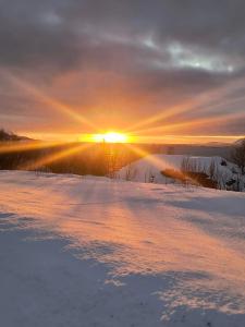 a sunset over a snow covered lake with the sun setting at Grønningbrygga in Grønning