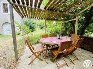 a wooden table and chairs under a pergola at La maison in Davejean