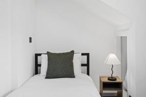 a white bed with a gray pillow and a lamp at The Reading Hub in Reading