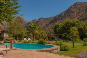 a swimming pool in a yard with mountains in the background at Refugio del Maipo Lodge in San José de Maipo