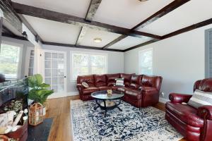 a living room with leather furniture and a table at Game Day Hub < 1 Mi to Stadium & Patriot Place! in Foxborough