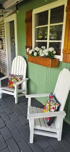 two white chairs sitting on the porch of a house at Little Tin House in Van Reenen