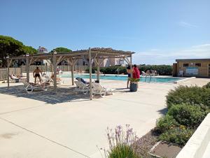 a swimming pool with people sitting in chairs next to a pool at les pieds dans l'eau 2 - Piscine chauffée in Le Barcarès