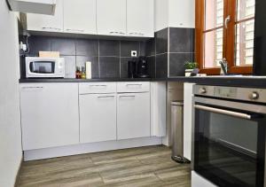 a kitchen with white cabinets and a microwave at La Petit Clé - Centre Ville in Sélestat +5 photos