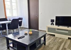 a living room with a coffee table and a flat screen tv at La Petit Clé - Centre Ville in Sélestat