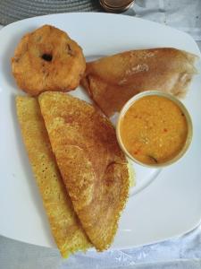 a plate of food with a sandwich and dipping sauce at Cocos cabana in Ilandaiyadi