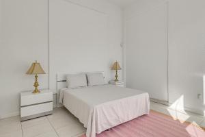 a white bedroom with a bed and two lamps at Near Apollo Beach! Bright Apt w/ Essentials in Ruskin