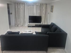 a living room with a black couch and a television at Maglovir Plumstead 5 rooms bulk in Plumstead