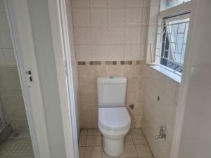 a small bathroom with a toilet and a window at Maglovir Plumstead 5 rooms bulk in Plumstead