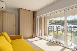 a living room with a yellow couch and a large window at Apartamenty Łukęcin Joy me 3 in Łukęcin