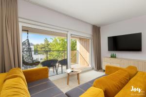 a living room with a yellow couch and a large window at Apartamenty Łukęcin Joy me 3 in Łukęcin