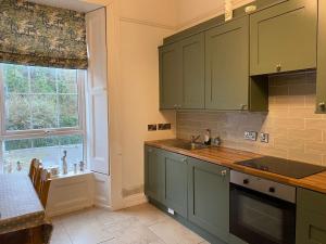 a kitchen with green cabinets and a sink and a window at Anns Sea View Suite in Cobh