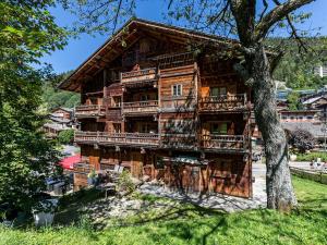 a large wooden house with balconies and a tree at Spacieux appart 5 ch au cœur du village, charme savoyard, WiFi, cheminée décorative - FR-1-437-51 in La Clusaz