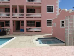a pink house with a swimming pool in front of it at Sandy Cove in Christ Church