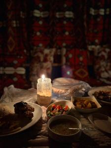 a table with plates of food and a candle at The Green Mirage free pickup in Siwa