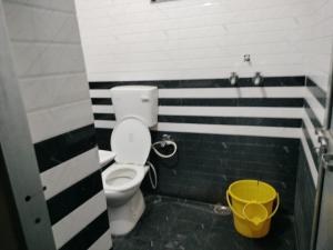 a bathroom with a toilet and a yellow bucket at Hotel Padamaa Palace in Varanasi