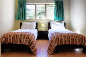 2 Betten in einem Zimmer mit grünen Vorhängen in der Unterkunft Victoria Apartments in Livingstone