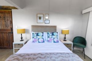 ein Schlafzimmer mit einem Bett, zwei Stühlen und zwei Lampen in der Unterkunft Falling Waters in Nottingham Road