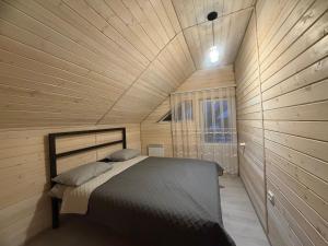 a bed in a room with a wooden ceiling at Карпатська Тиша in Utoropy