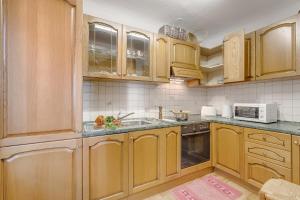 a kitchen with wooden cabinets and a sink at Casa Naima: Family House | Terrace & Peaceful Location - Happy Rentals in Breno