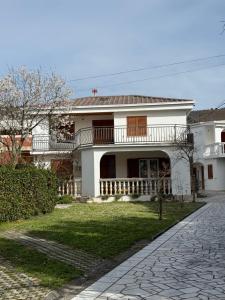 a white house with a porch and a balcony at House Jesenova in Selce