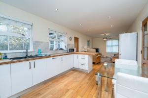 a kitchen with white cabinets and a glass table at Abbey View in Old Deer