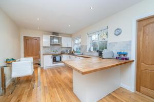 a kitchen with white cabinets and a wooden counter top at Abbey View in Old Deer +10 photos
